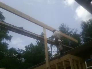 Carpenter setting a ridge beam over a new addition frame — Ice Dam Removal by Roofing Brothers in Boomer