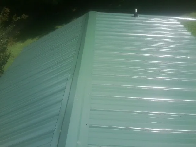 New green metal panels meeting at the ridge of a roof — Flat Roof Repair work by our crew in Boomer