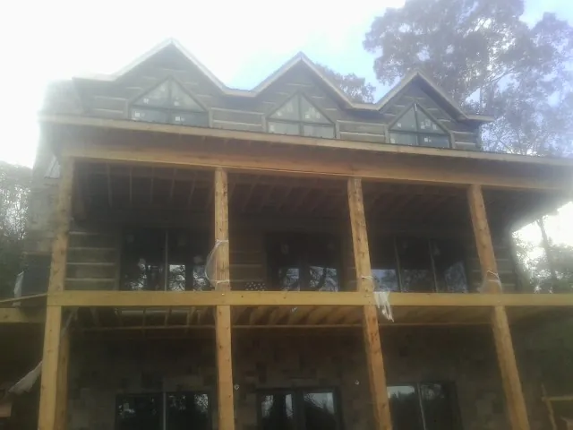Dormers and porch framing on a large log home under construction — Roof Coating work by our crew in Boomer