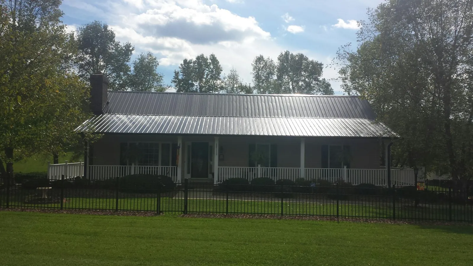 Gray metal roof on a brick ranch with a full width front porch — Gutter Guard Installation work by our crew in Boomer