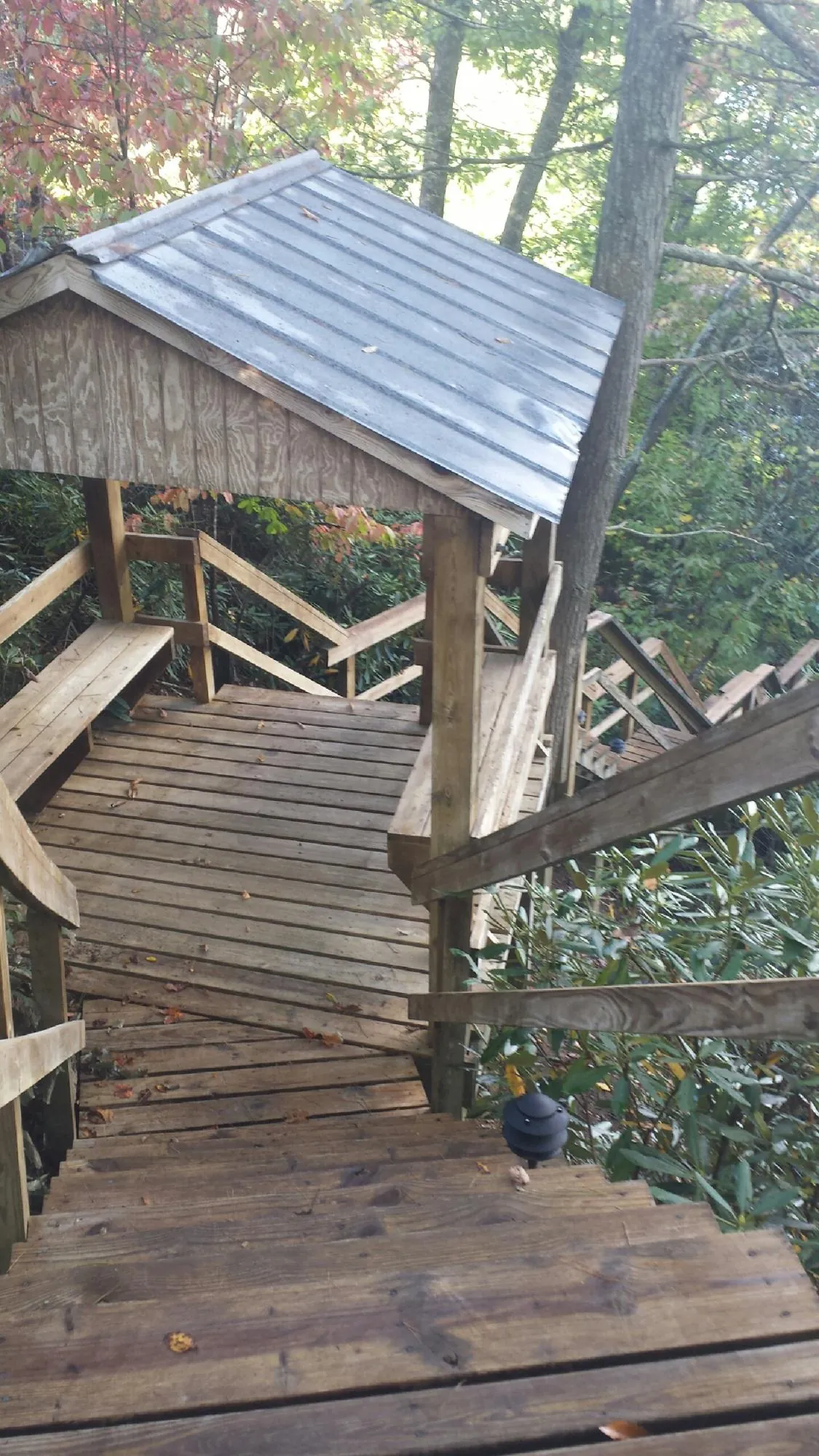 Metal roofed shelter over wooden steps on a wooded walkway — Skylight Repair & Installation work by our crew in Boomer